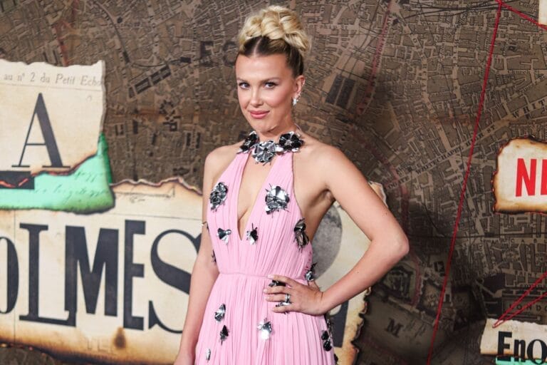 Millie Bobby Brown: Wears a pink dress with shimmering floral details and a deep neckline. Jewelry includes…