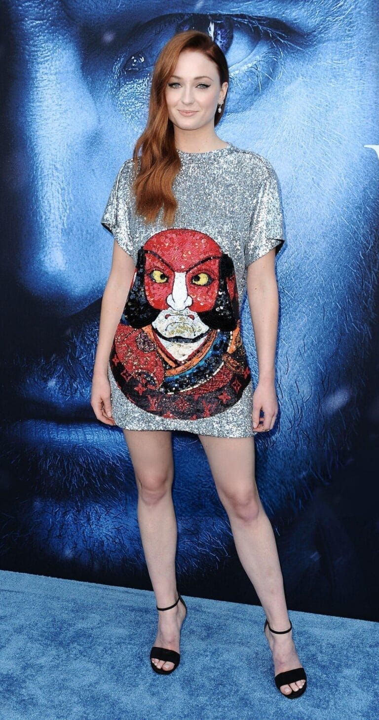 Sophie Turner: Wears a short silver sequin dress with a colorful design on the front.…