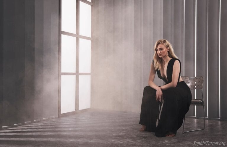 Sophie Turner: Seated on a metal chair, wearing an elegant black jumpsuit with a deep neckline…