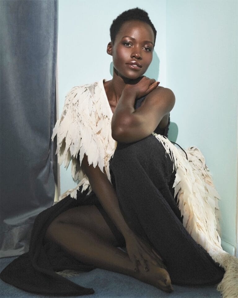 Lupita Nyong’o: Luce un vestido largo negro con detalles de plumas blancas en los hombros. Está…