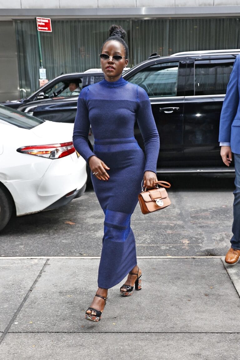 Lupita Nyong’o: Wears a long-sleeved, fitted blue outfit, paired with dark sunglasses…