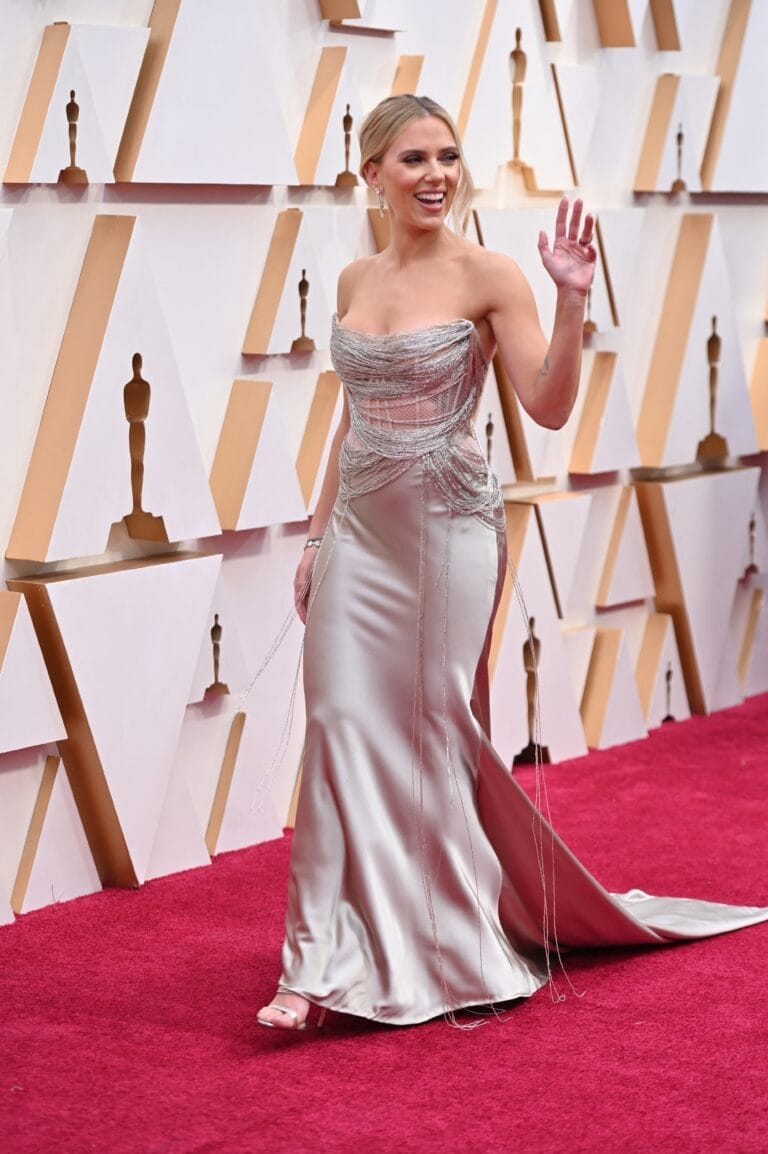 Scarlett Johansson: Wears an elegant sleeveless silver dress with sparkling details and a long train.…