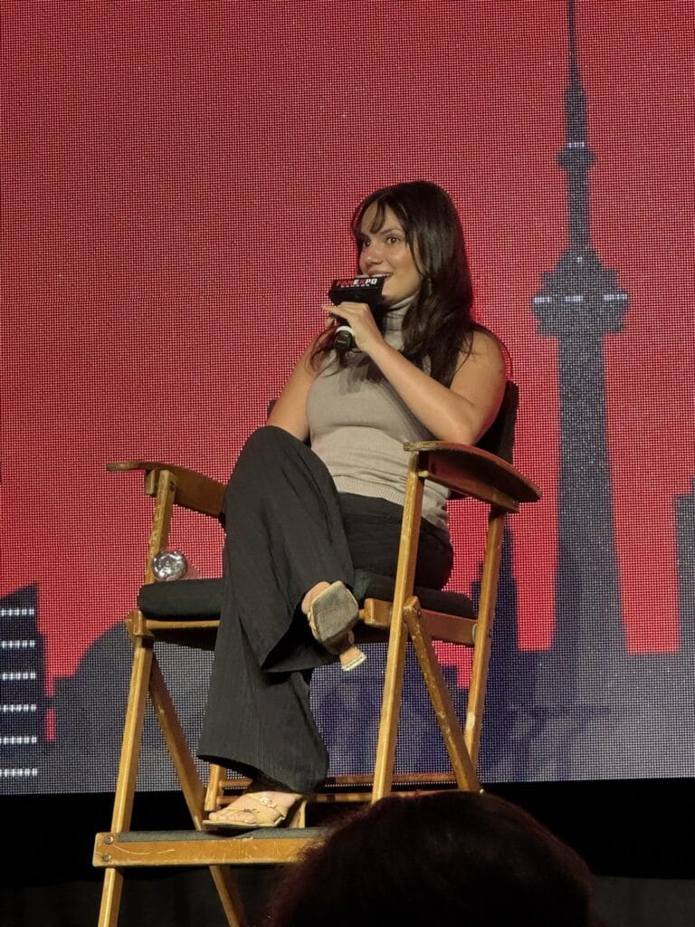 Dafne Keen: Wears a beige sleeveless top and black pants. Wears sandals…