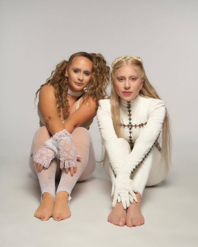 Lady Gaga: Long blonde hair with braids wrapped around her head, and a white outfit...
