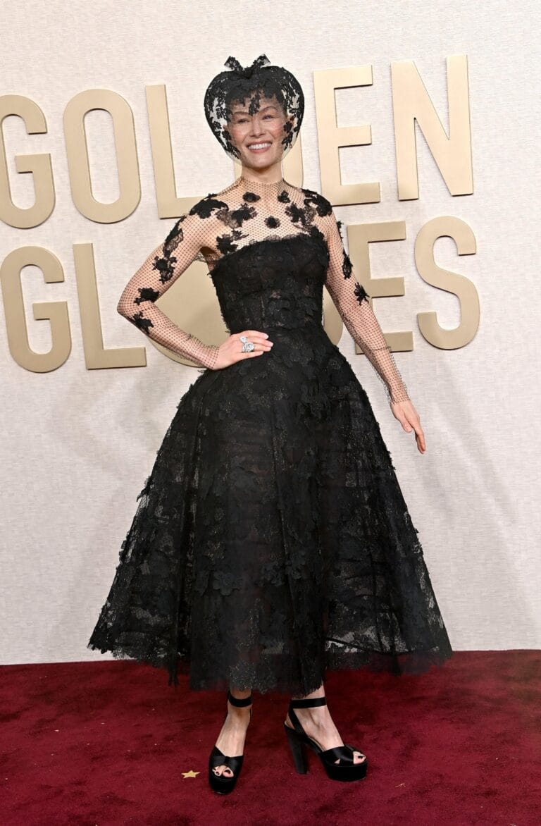 Rosamund Pike: Con un vestido negro de encaje que destaca por sus detalles florales, la figura…
