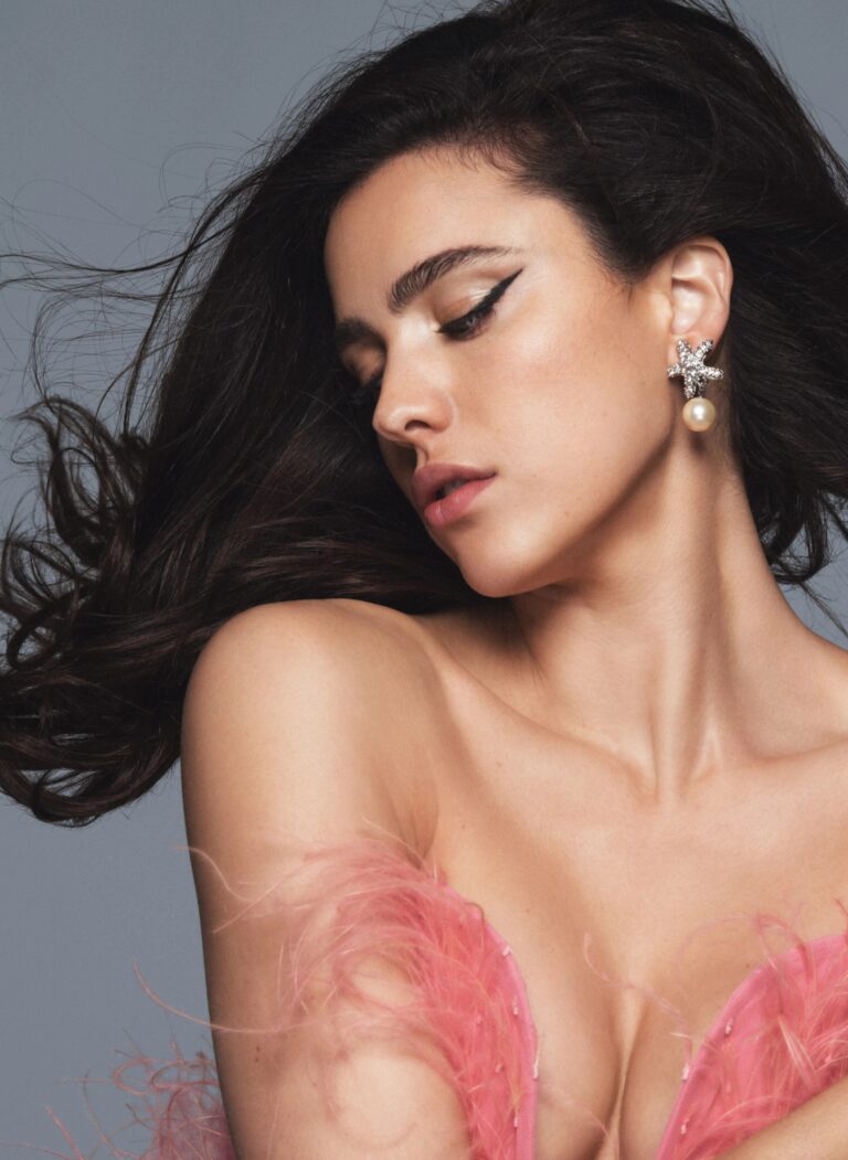 Margaret Qualley: Wears a dress with pink feather straps and shiny details. Wears eye-catching earrings…