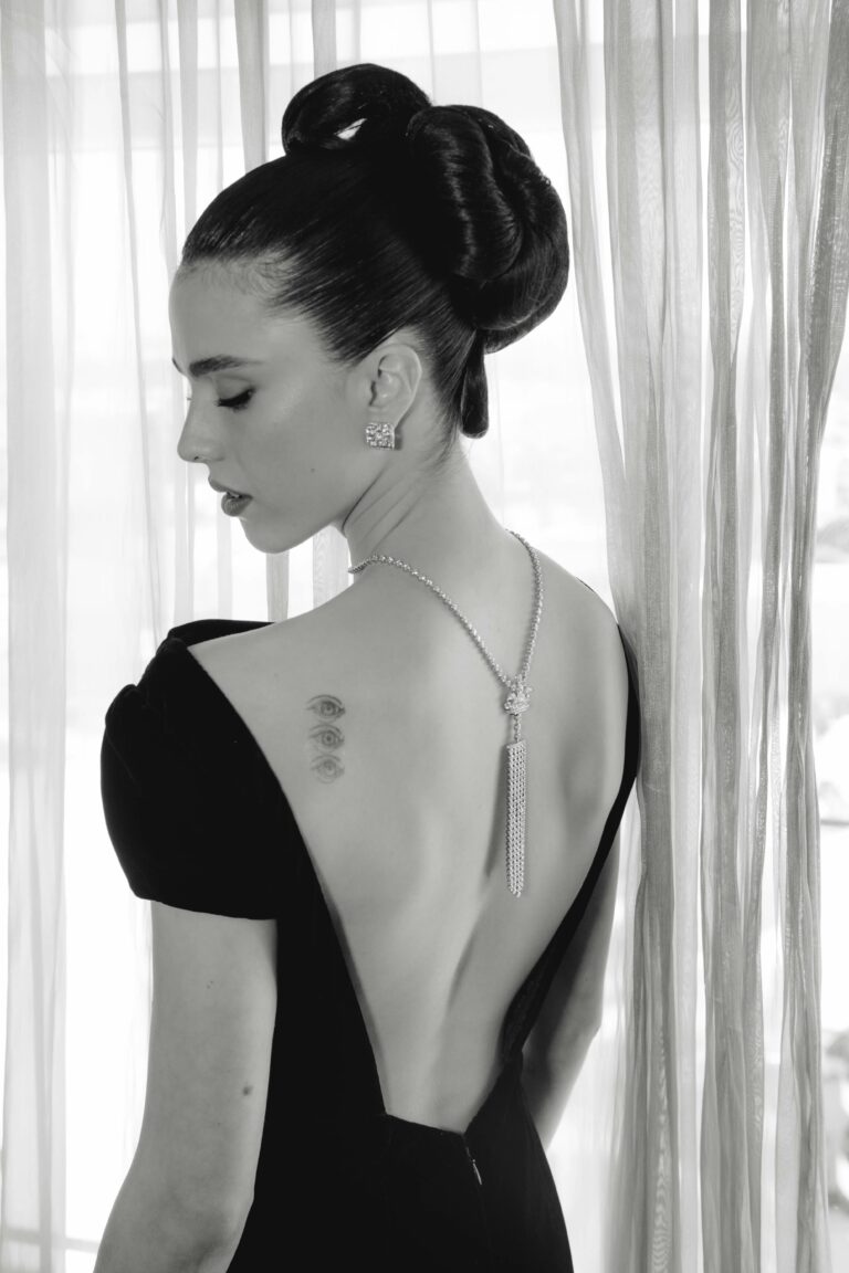 Margaret Qualley: Wears an elegant black dress with a deep open back, adorned with…