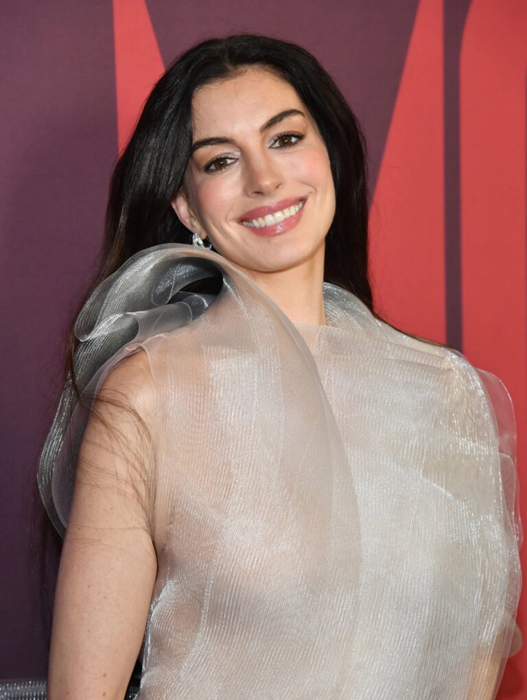 Anne Hathaway: Wearing a translucent mesh piece with a structured, voluminous design on the…