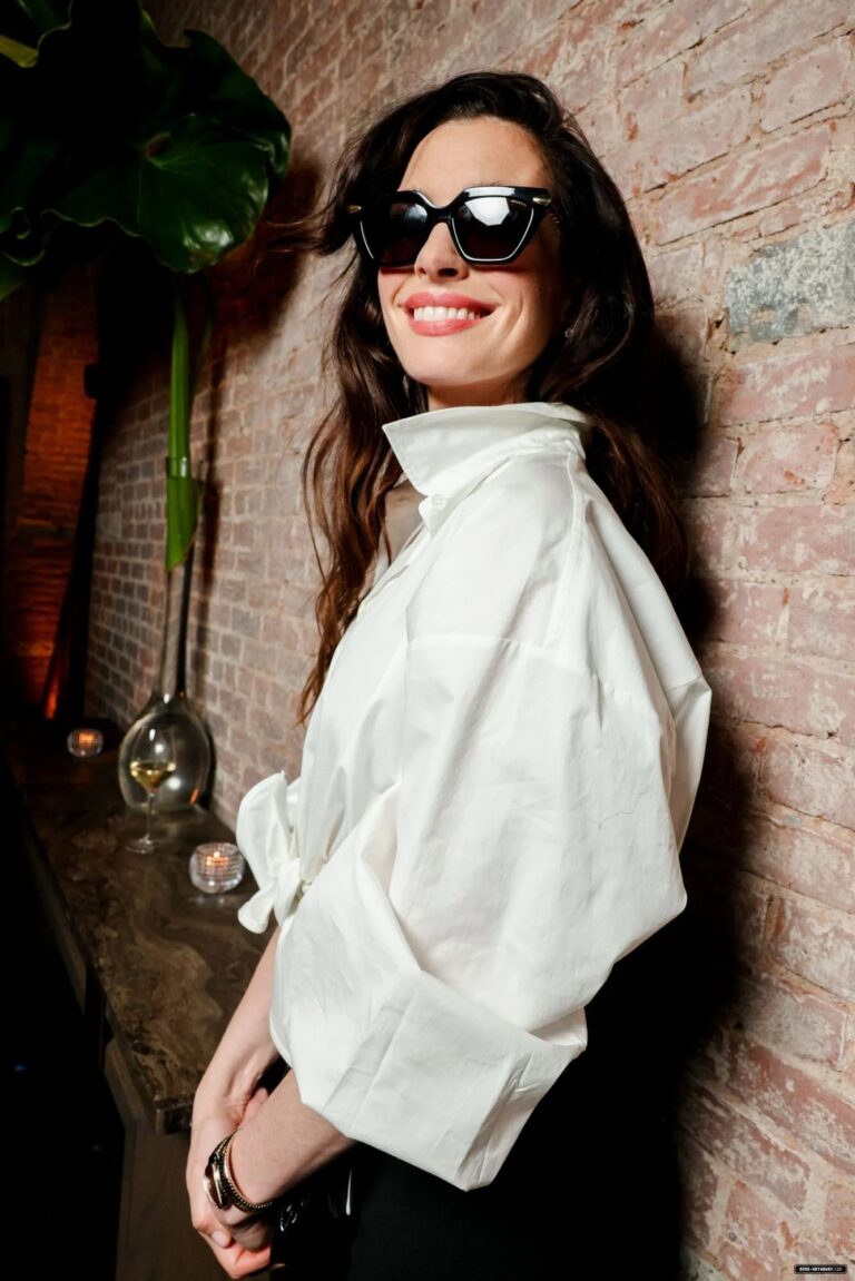 Anne Hathaway: A figure in black sunglasses with long, loose hair. Wearing…