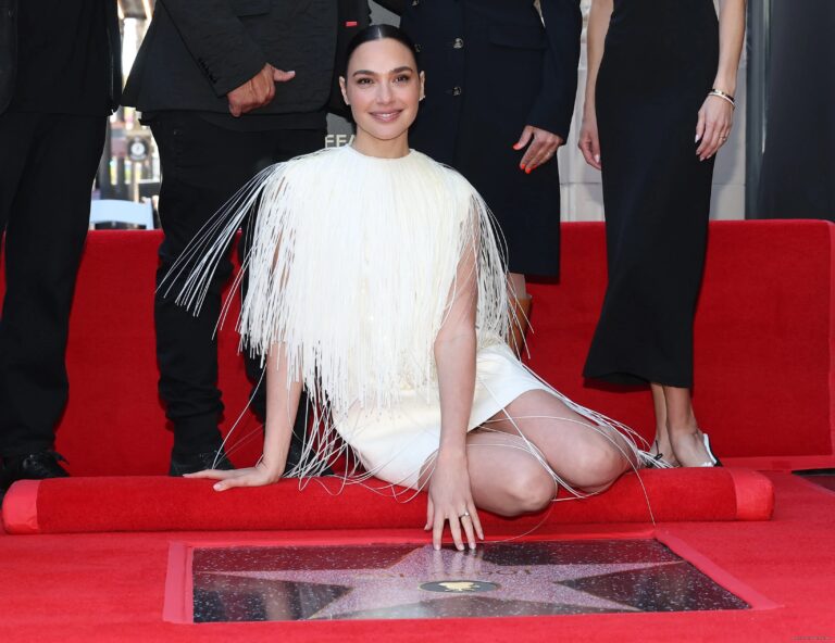 Gal Gadot: Wears a white dress with long fringe falling from the shoulders, creating a…
