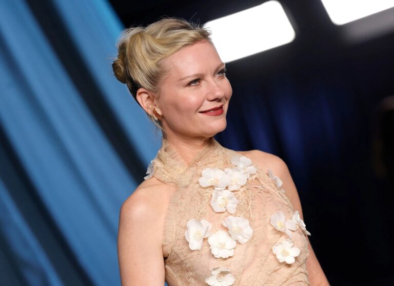 Kirsten Dunst: Blonde hair elegantly styled, in a beige dress decorated with raised white flowers.…