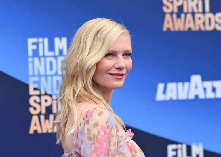 Kirsten Dunst: Wavy blonde hair, wears a colorful dress with a floral print…