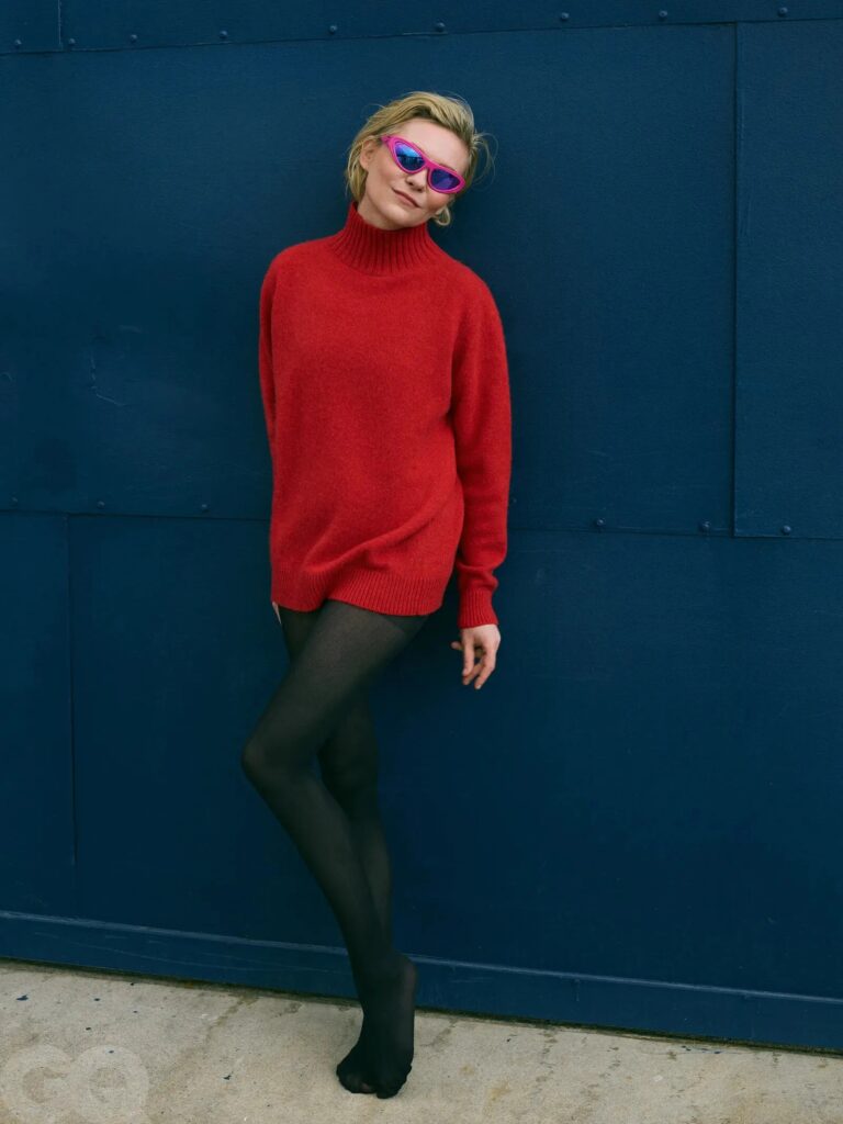 Kirsten Dunst: A thick red knit sweater paired with opaque black tights. Wears glasses…