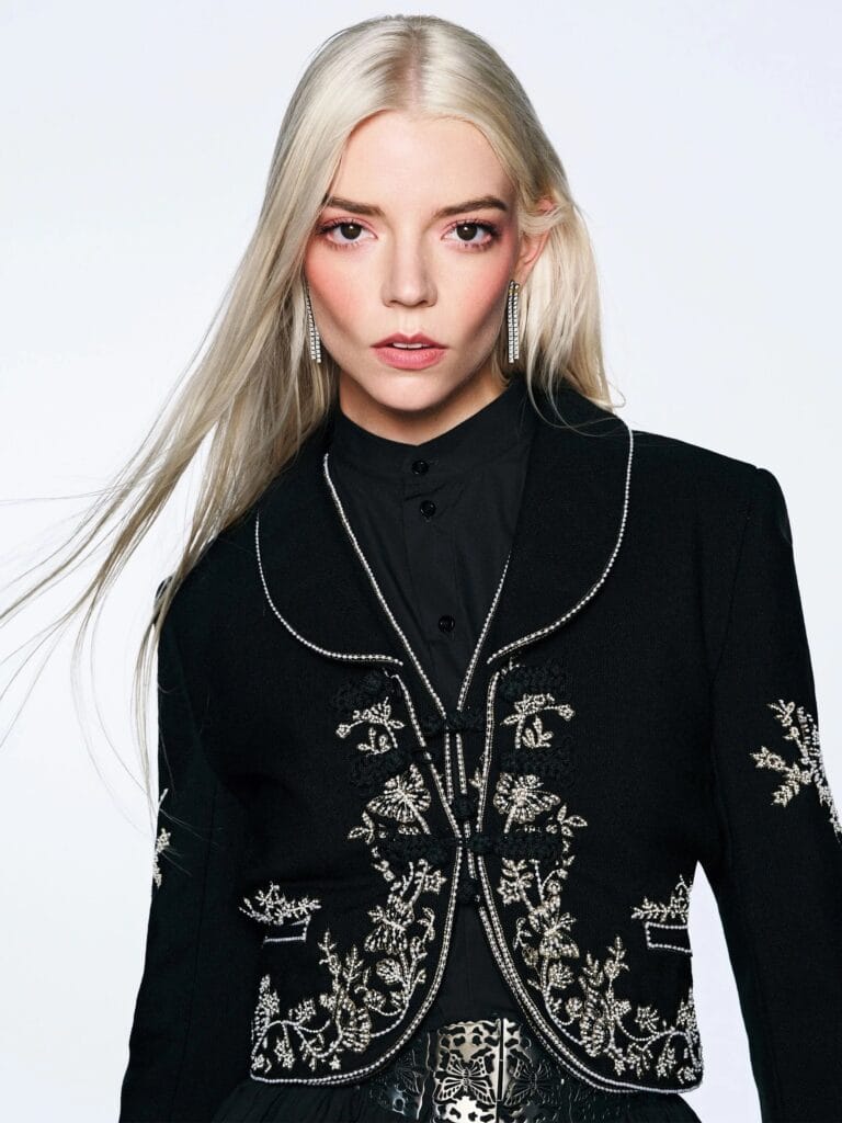 Anya Taylor-Joy: Wears an elegant black coat with detailed embroidery, contrasting with a black blouse…
