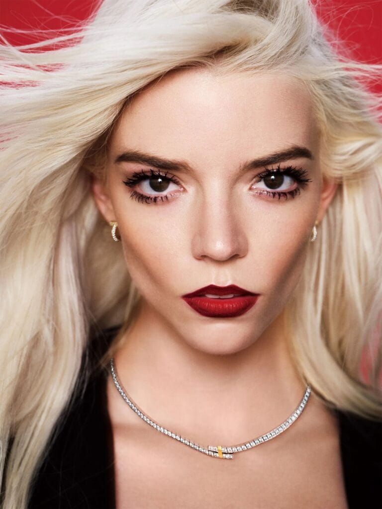 Anya Taylor-Joy: Wears a bold red lipstick that stands out against the vibrant background and a jewel…