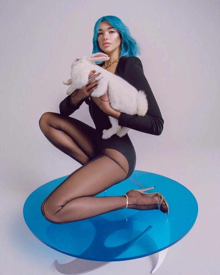 Dua Lipa: Luce un bodysuit negro ajustado y elegante, combinado con medias transparentes que resaltan las…