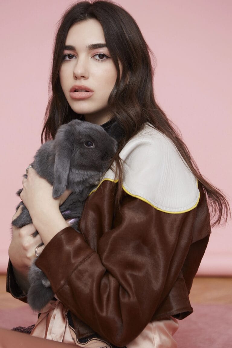 Dua Lipa: Luce una chaqueta de cuero marrón con detalles en blanco y amarillo, abrazando un…