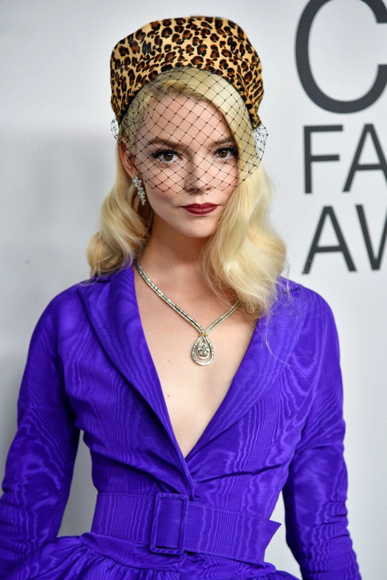 Anya Taylor-Joy: Wears a purple dress with a deep neckline and a belt that accentuates the…
