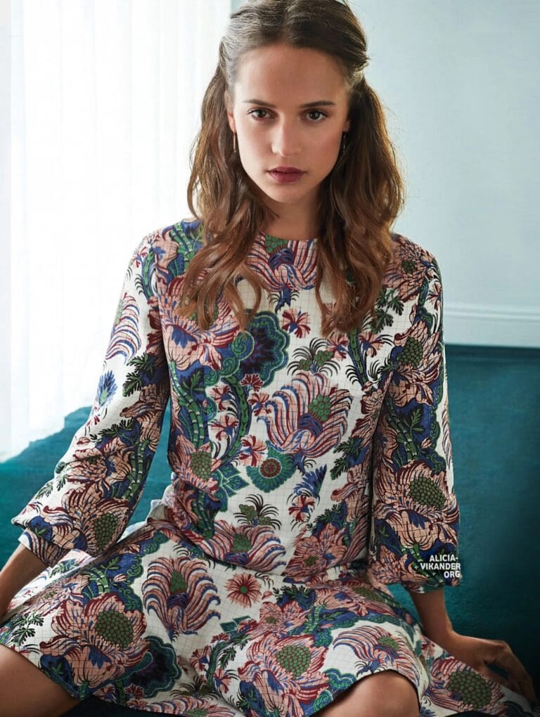 Alicia Vikander: Wears a short long-sleeved dress with a vibrant floral print in tones…