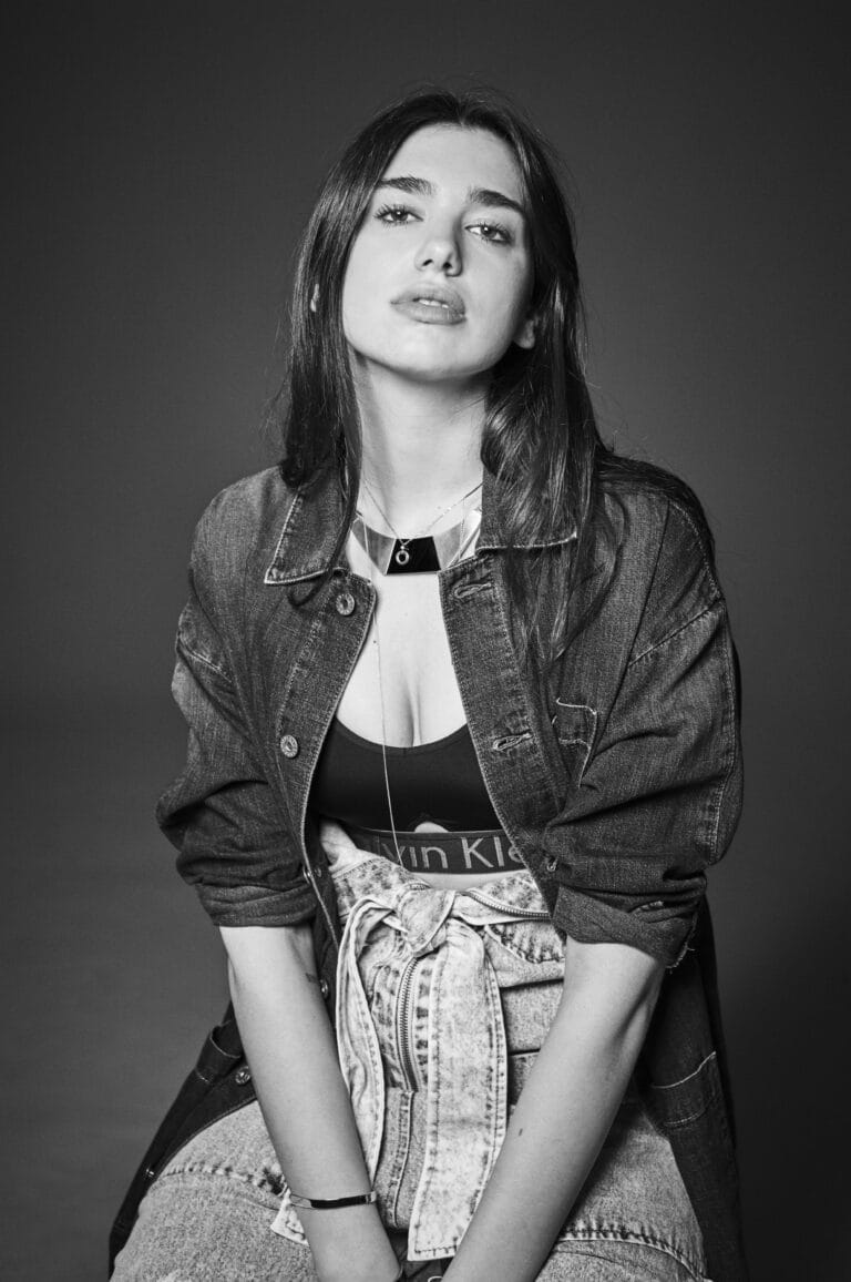 Dua Lipa: Wears an oversized denim jacket over a black Calvin Klein top, showing…