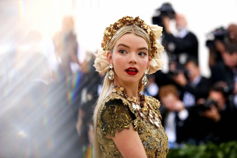 Anya Taylor-Joy: Wears a striking gold dress with ornate details, paired with a flower crown…