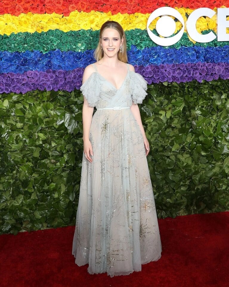 Rachel Brosnahan: Wears an elegant long light blue dress with sparkling details and sleeves…