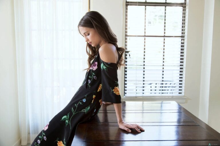 Alicia Vikander: Poses on a wooden table in a long-sleeved black dress and…