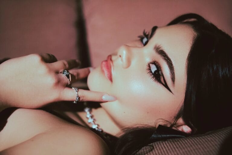 Ariana Greenblatt: Wears a sophisticated look, reclining against a soft, textured backdrop, with dramatic eye makeup…
