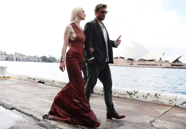 Anya Taylor-Joy: Wears a fitted burgundy dress with a deep neckline while walking with…