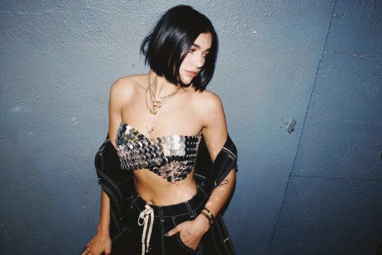 Dua Lipa: Luce un top metálico sin mangas que resalta su figura, combinado con un pantalón…