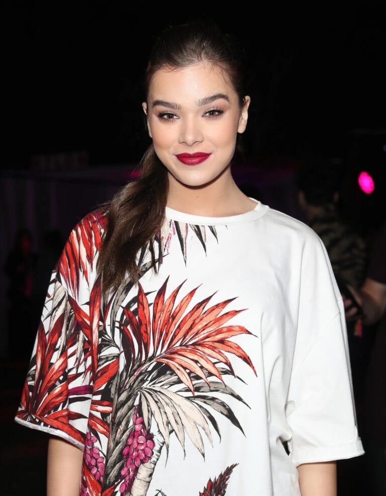Hailee Steinfeld: Wears an oversized white t-shirt with a vibrant print of red and green leaves,…