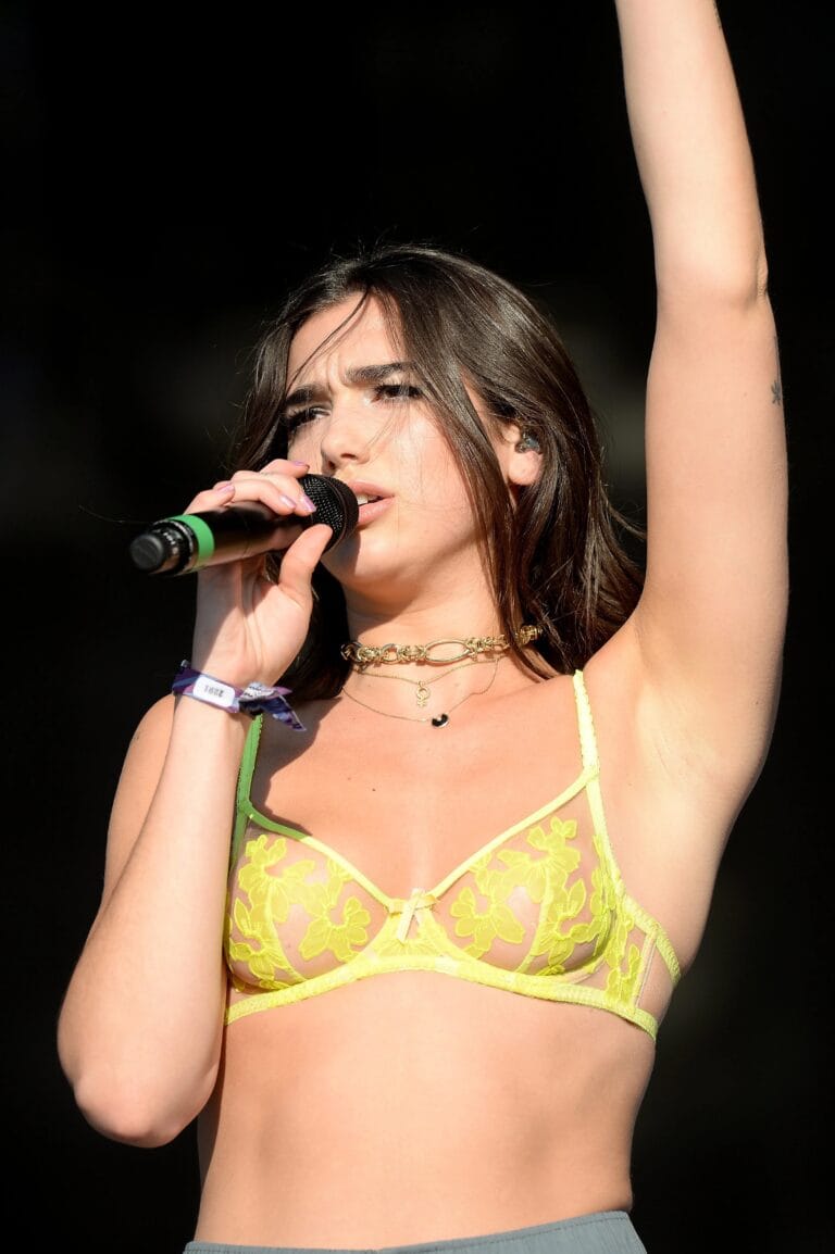 Dua Lipa: Luce un sujetador de encaje amarillo brillante, con detalles florales, mientras sostiene un micrófono…