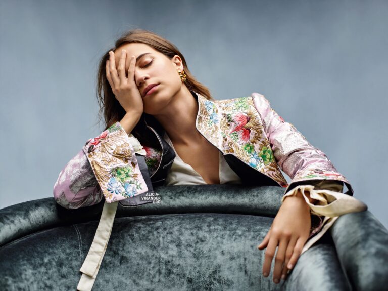 Alicia Vikander: Wears a vibrantly embroidered jacket over a white blouse, resting her head…