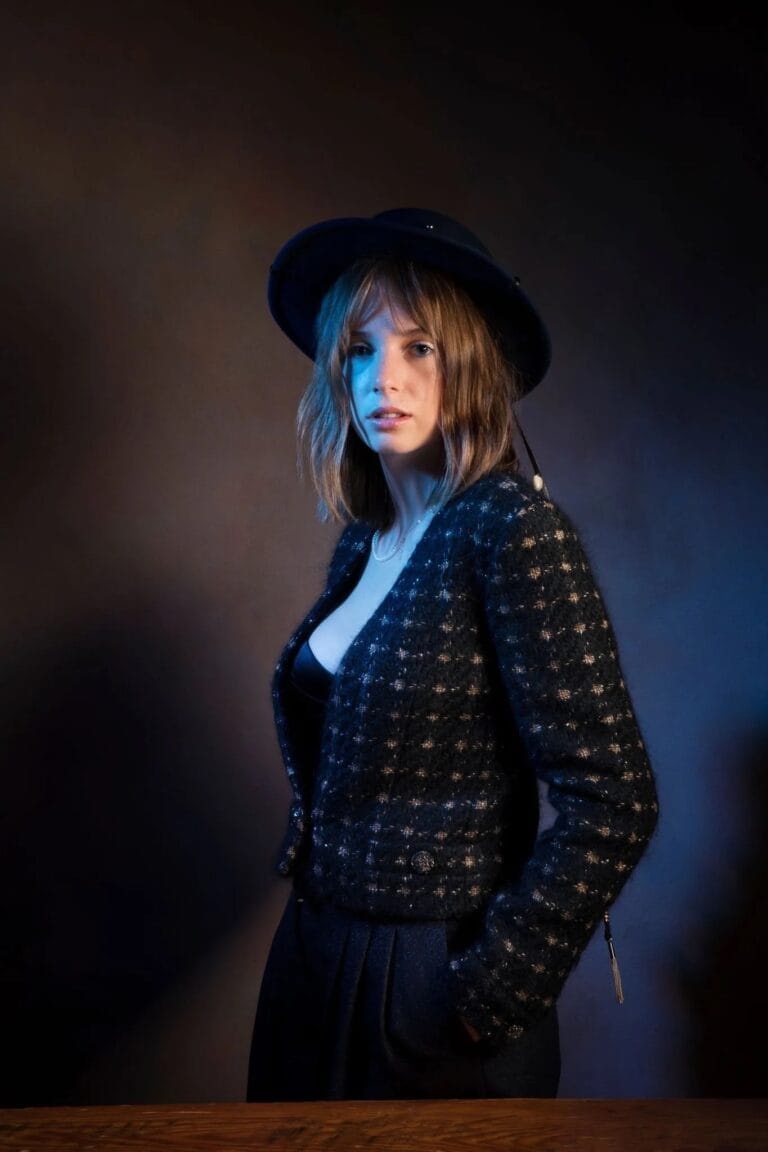 Maya Hawke: Luce un elegante chaquetón negro con texturas brillantes, complementado con un sombrero de ala…