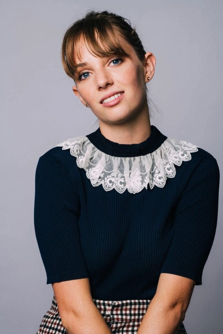 Maya Hawke: Luce un top de manga corta en tono azul marino, adornado con un delicado…