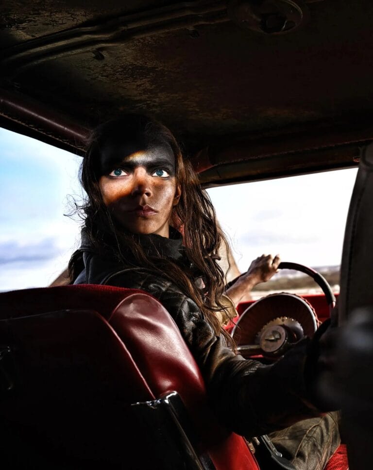Anya Taylor-Joy: Wears a dark leather jacket and sits behind the wheel of a classic car,…