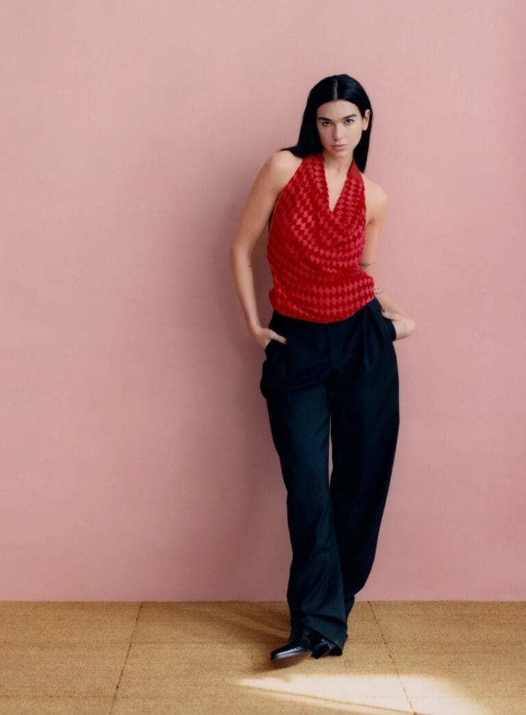 Dua Lipa: Luce una blusa roja con un diseño de rombos, que cae suavemente sobre unos…