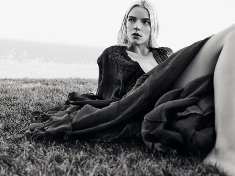 Anya Taylor-Joy: Posa sentada sobre la hierba, con un vestido largo y fluido de tonalidad oscura…