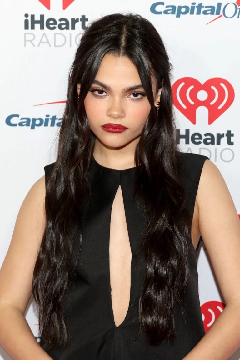 Ariana Greenblatt: Wears a fitted black dress with a deep plunging neckline in the shape of…