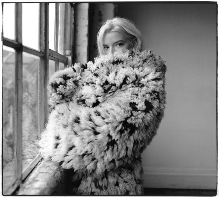 Anya Taylor-Joy: Wears a fluffy oversized coat in light and dark tones, hugging herself while…