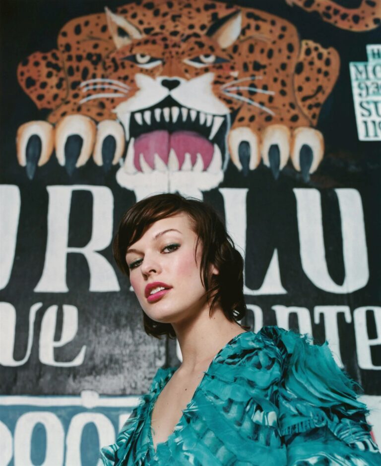 Milla Jovovich: Wears a blue dress with ruffle details on the sleeves and bodice.…