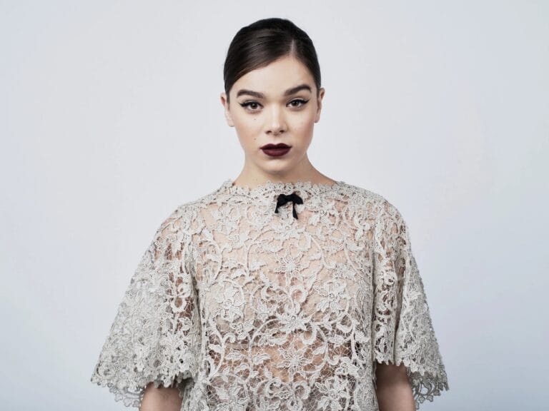 Hailee Steinfeld: Wears a delicate lace top with a small black bow at the neck,…
