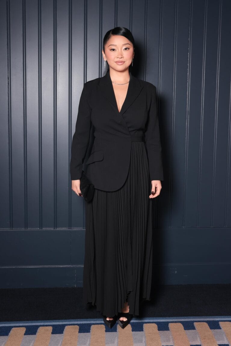 Lana Condor: Wears a black blazer and long pleated skirt set that creates an air…
