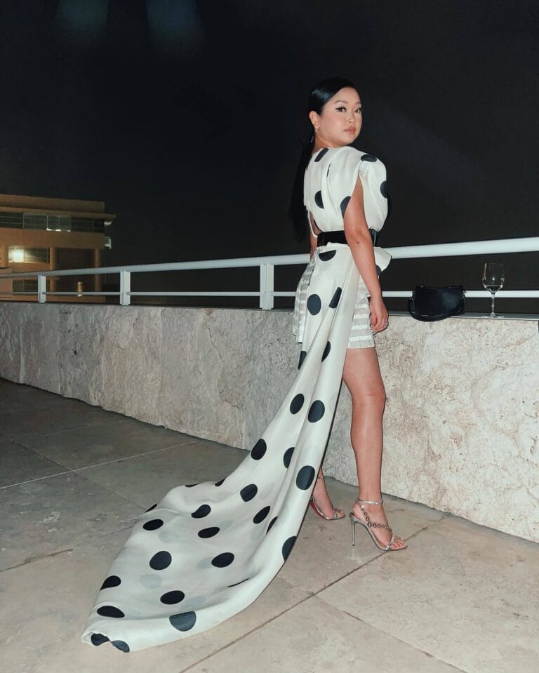 Lana Condor: Wears a white dress with large black polka dots that flows elegantly behind…