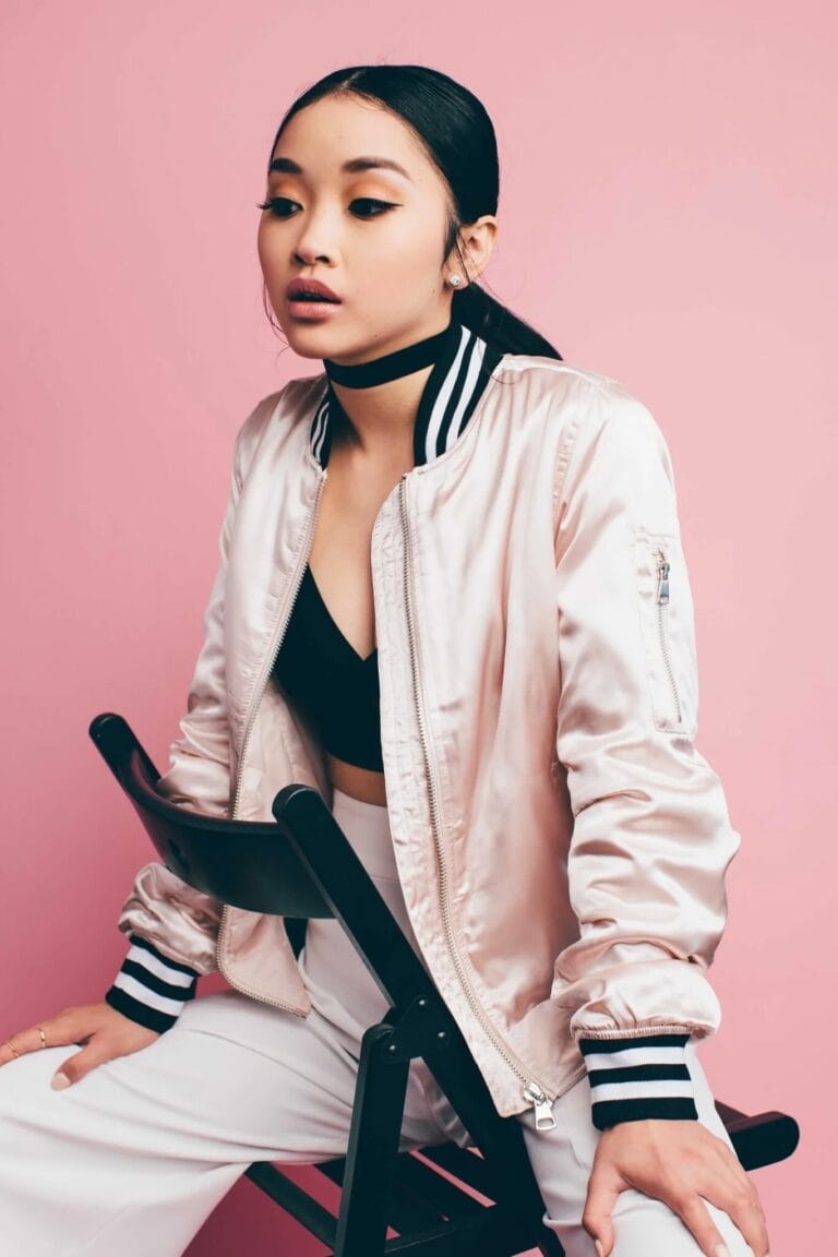 Lana Condor: Wears a pink satin jacket with black and white details, paired with a…