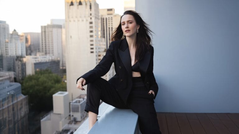Rachel Brosnahan: Poses in an urban setting, wearing a black pantsuit with a…