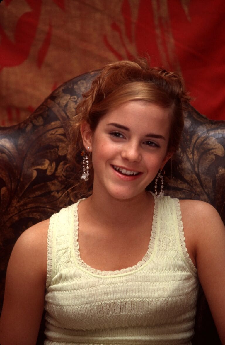 Emma Watson: Wears a light-colored sleeveless blouse with a textured design that highlights…