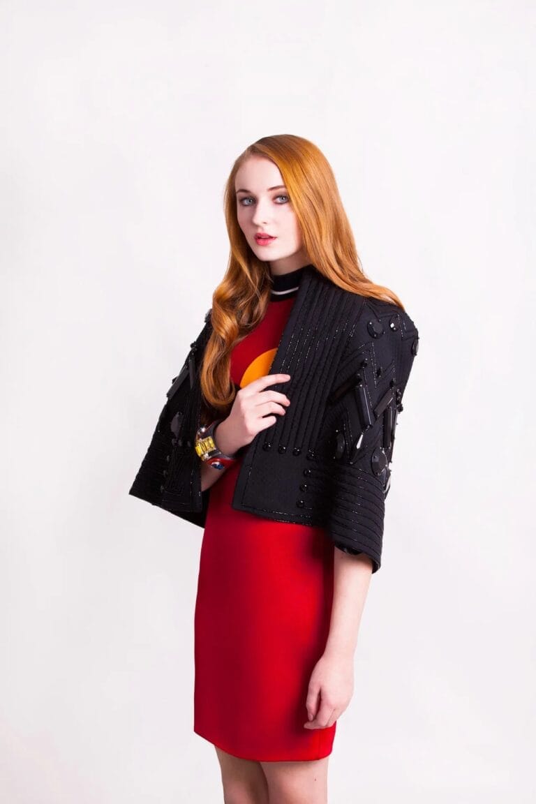 Sophie Turner: Wears a fitted red dress that flatters her figure, paired with a black jacket…