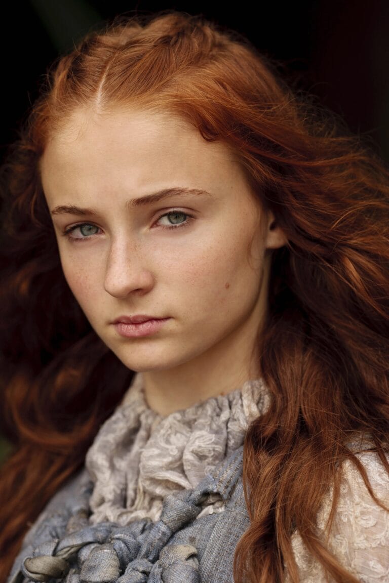 Sophie Turner: Wears a soft-textured blouse with a gathered neckline and gray details,…