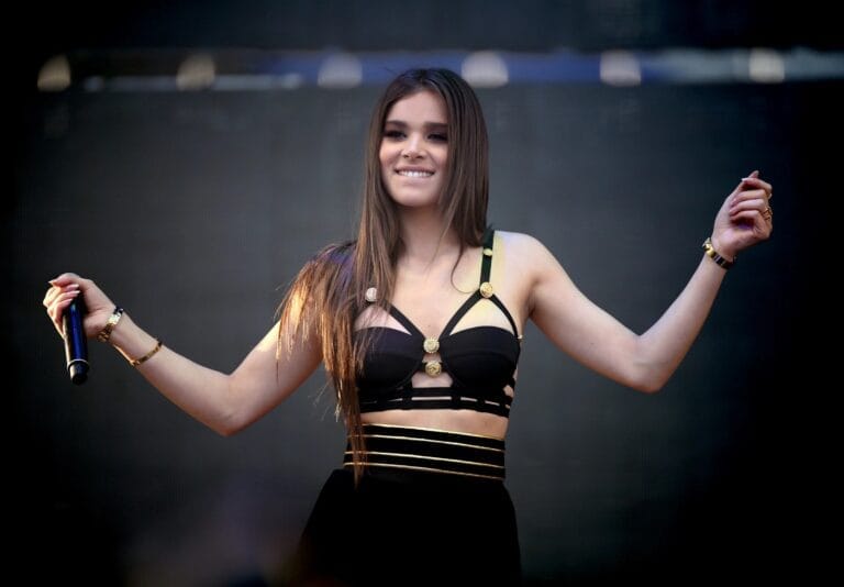 Hailee Steinfeld: Luce un top negro con tirantes decorados y una falda a juego, mostrando un…